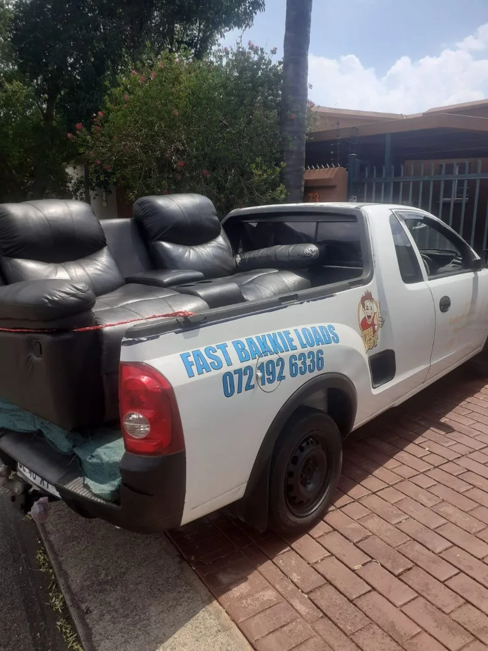 Black leather sofa loaded on white bakkie